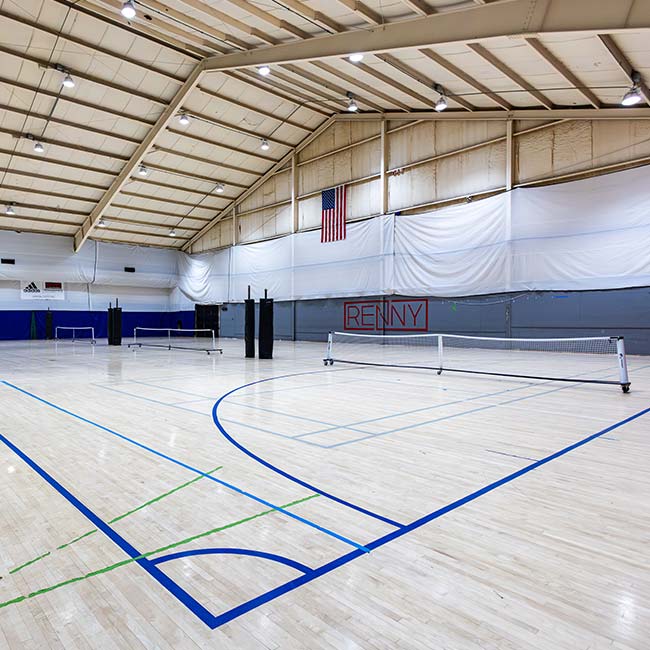Indoor sports gym with wood floor, tennis nets, and Indoor Volleyball Court Rentals in Pittsburgh.