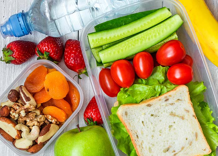 A packed lunch with a sandwich, vegetables, fruit, and nuts, perfect for Summer Sports Camps.